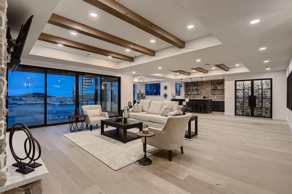 Spacious lower-level family room with modern sofas and sliding doors in a custom home by Sheffield Homes in Franktown, CO