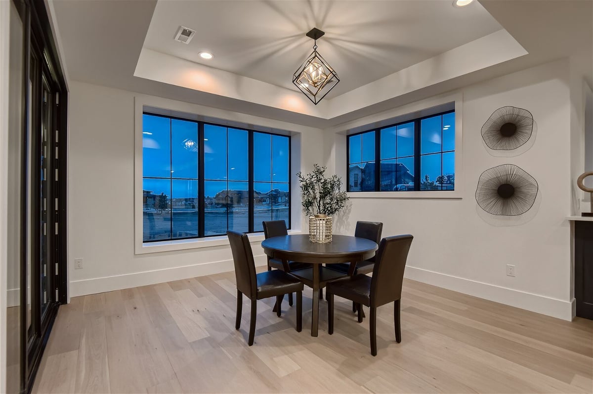 Table in a dining room under a fancy chandelier with sliding windows in a custom home by Sheffield Homes in Franktown, CO