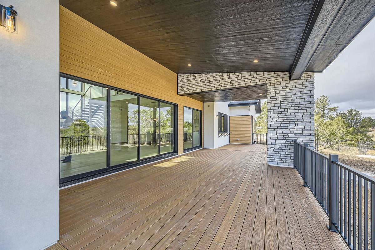 Balcony with a metal fence, stone accent pillar beam, and a top deck in a custom home by Sheffield Homes in Franktown, CO