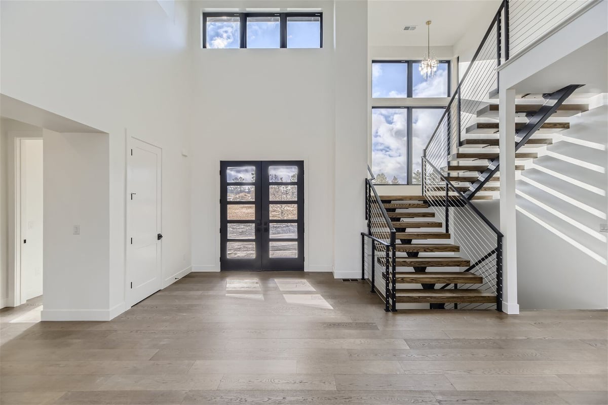 Bright foyer with a black access door and marble flooring in a custom home by Sheffield Homes in Franktown, CO