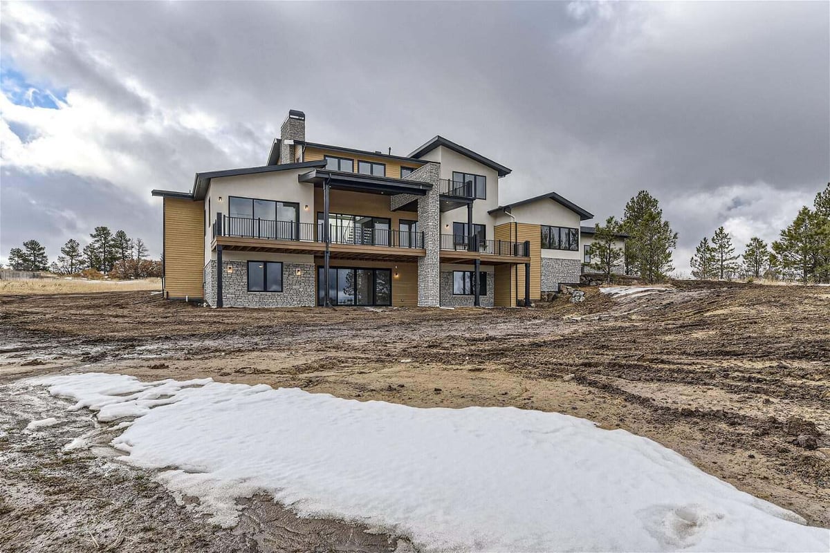 Daylight exterior rear view of a custom home with the backyard by Sheffield Homes in Franktown, CO