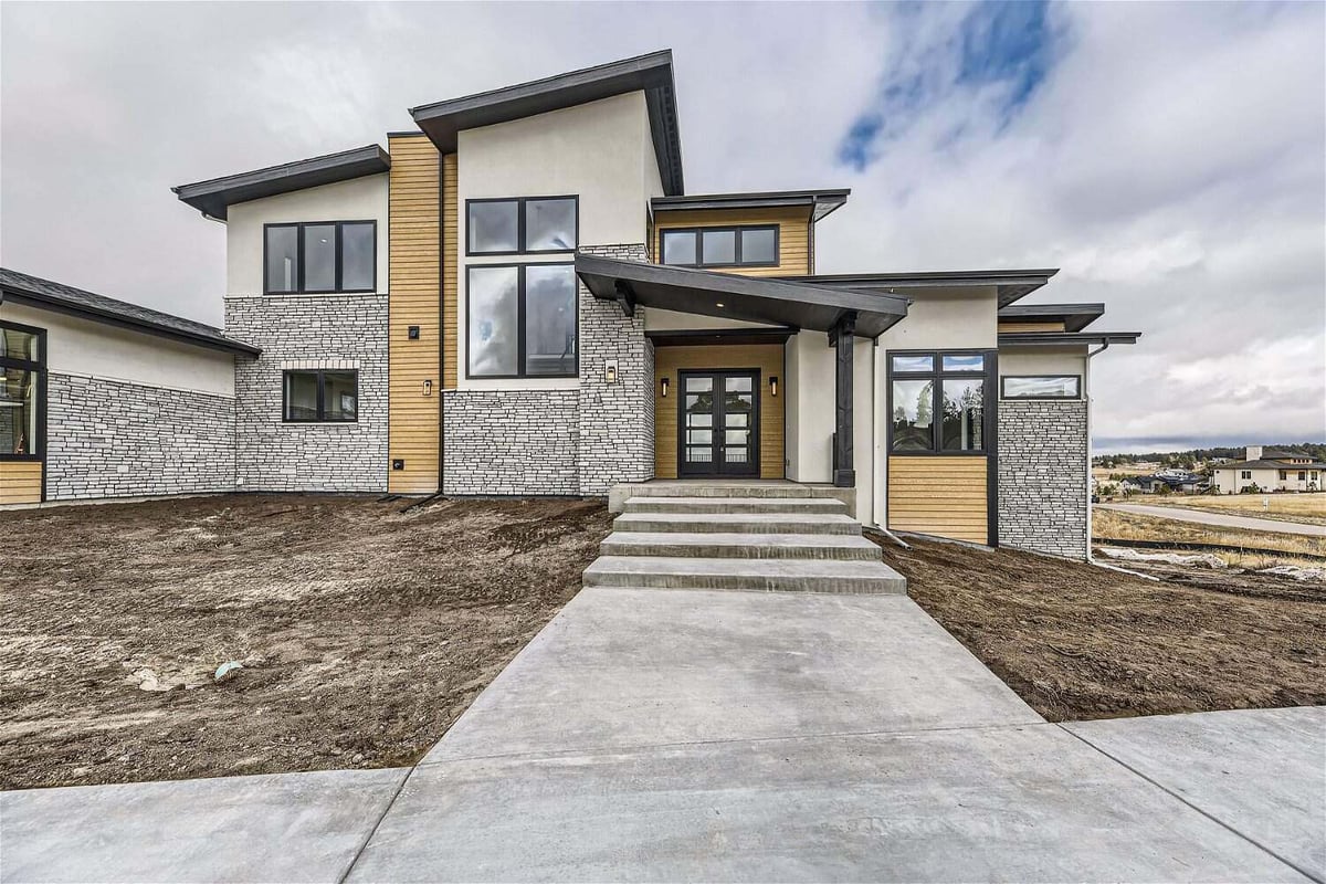 Exterior front main entrance of a custom home with stone accents and a paved pathway by Sheffield Homes in Franktown, CO