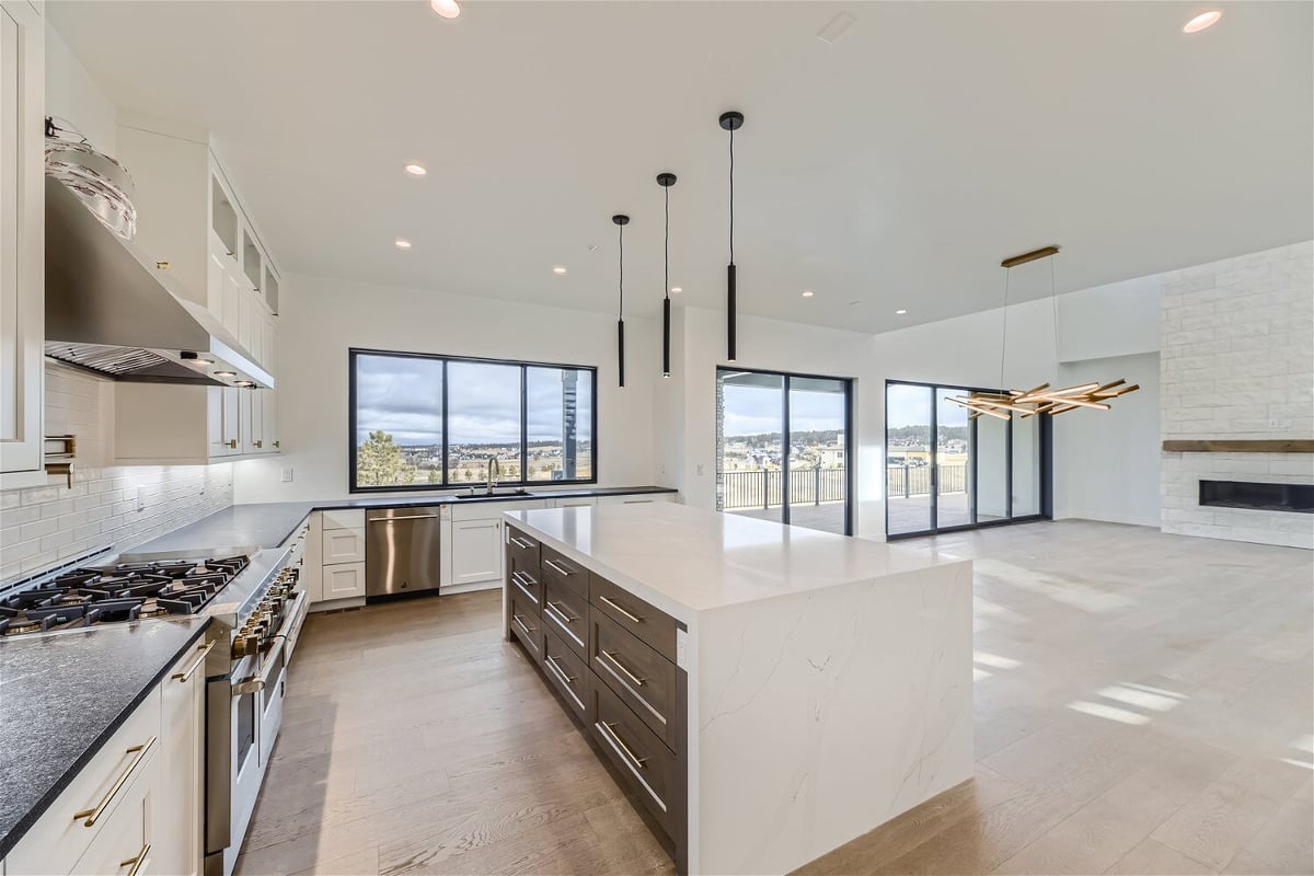 Kitchen island with cabinets and a smooth countertop in front of the stove in a home by Sheffield Homes in Franktown, CO