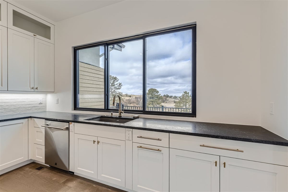 Kitchen sink with cabinets and a faucet under a sliding window in a custom home kitchen by Sheffield Homes in Franktown, CO