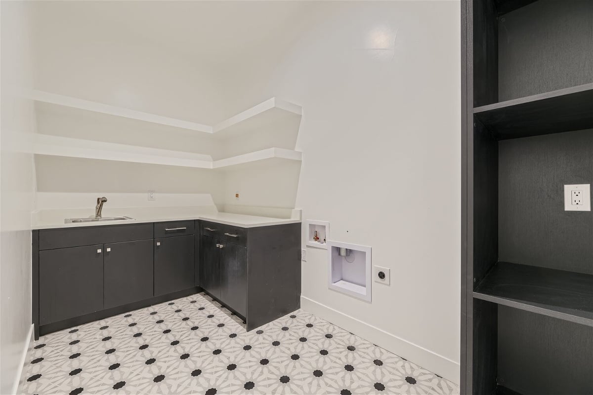 Laundry room with wooden cabinetry, a sink, and built-in storage niches in a custom home by Sheffield Homes in Franktown, CO