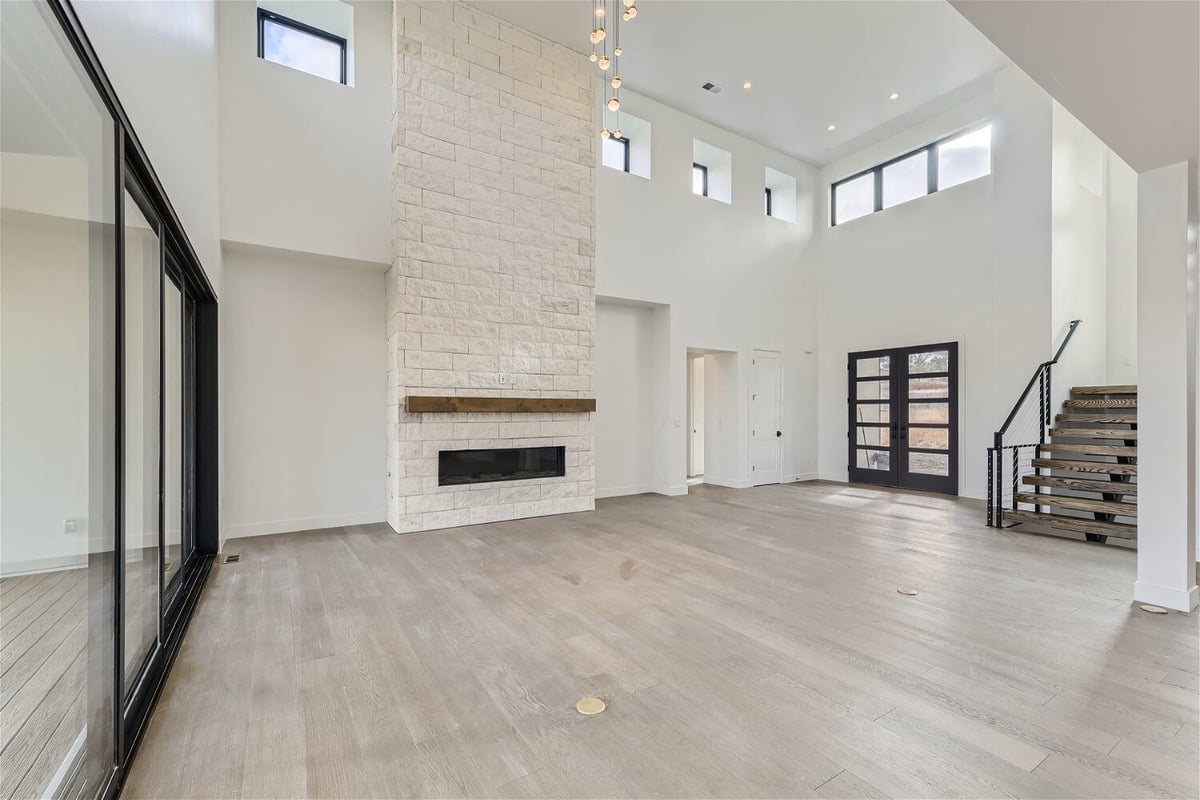 Living room with a stair landing, large sliding doors, and a fireplace in a custom home by Sheffield Homes in Franktown, CO