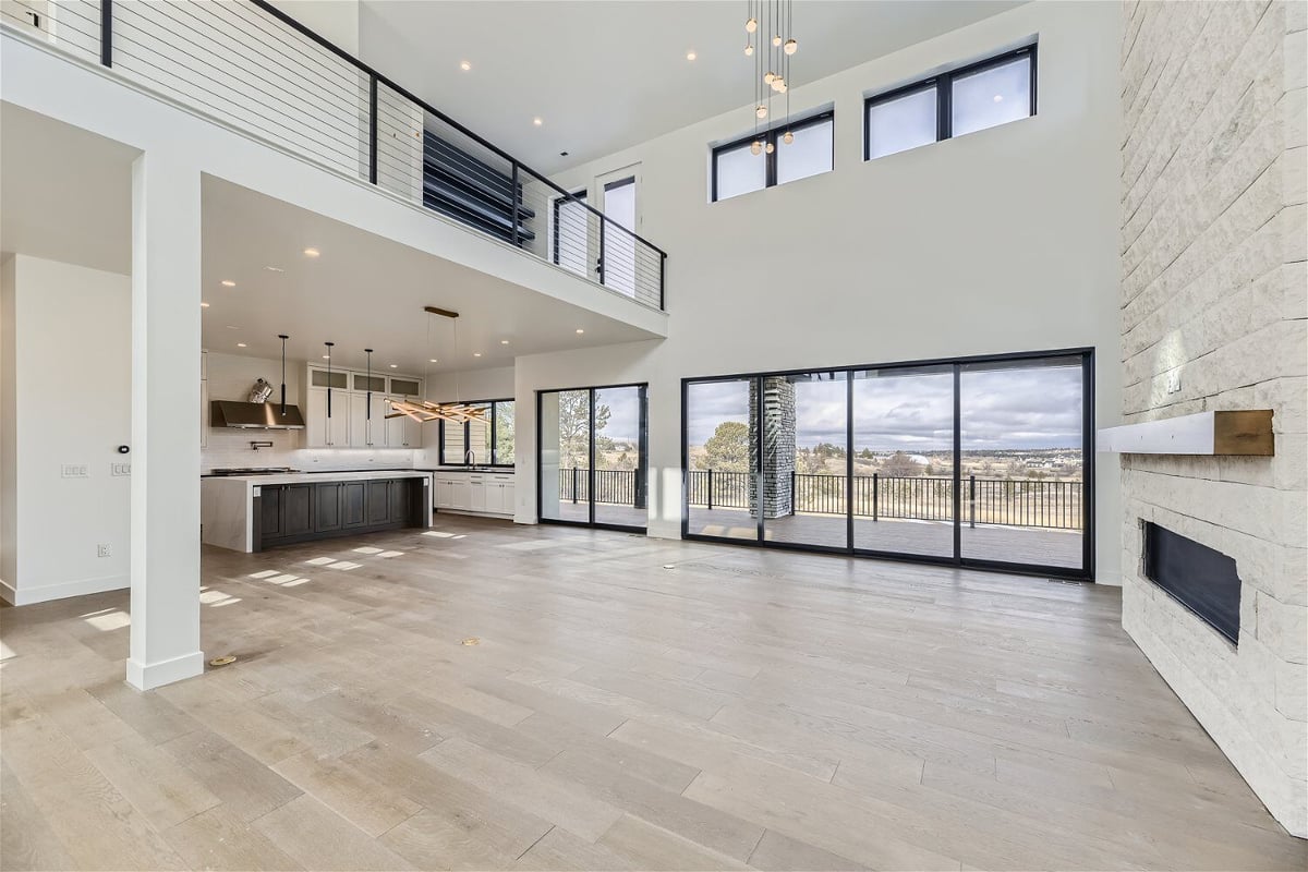 Living room with multiple large sliding doors and an open kitchen in a custom home by Sheffield Homes in Franktown, CO