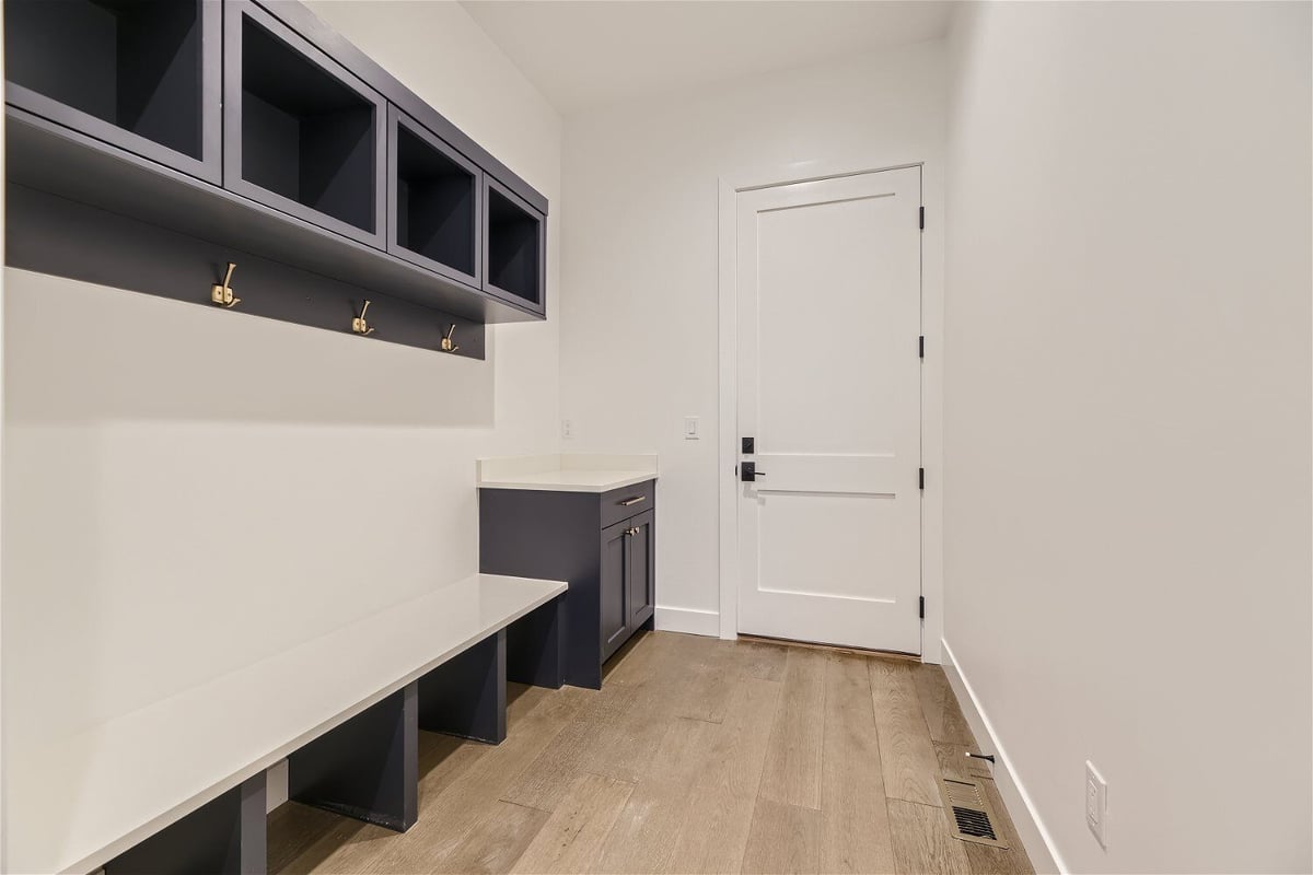 Mudroom with a bench, and wall-mounted shelves with hanging hooks in a custom home by Sheffield Homes in Franktown, CO