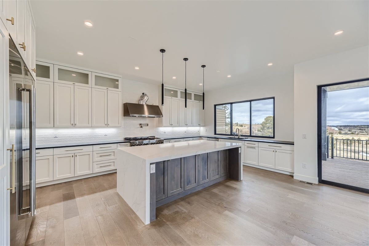 Open kitchen with an island and sleek white cabinetry in a custom home living room built by Sheffield Homes in Franktown, CO