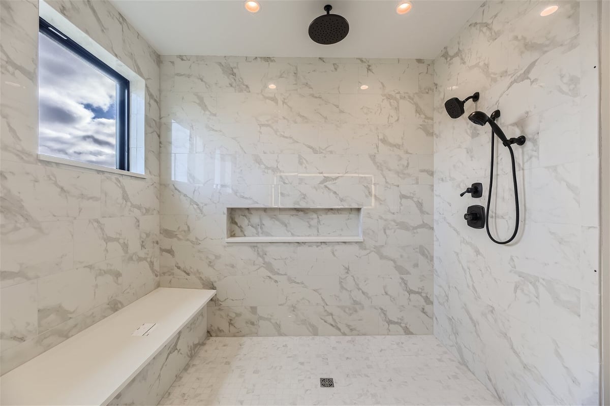 Primary bathroom with multiple shower fixtures, and a sliding window in a custom home by Sheffield Homes in Franktown, CO