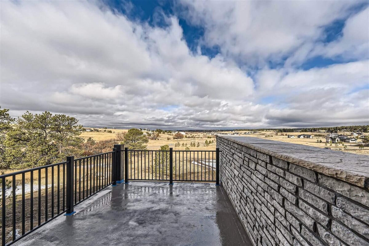 Private balcony with metal fence a stone accent wall and expansive views in a custom home by Sheffield Homes in Franktown, CO