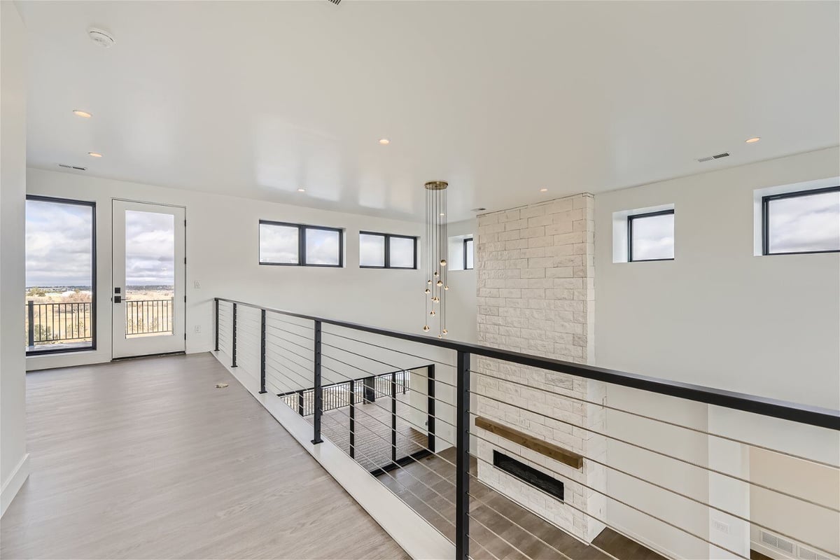 Second-floor loft with a hallway railing and a view of the lower hall in a custom home by Sheffield Homes in Franktown, CO