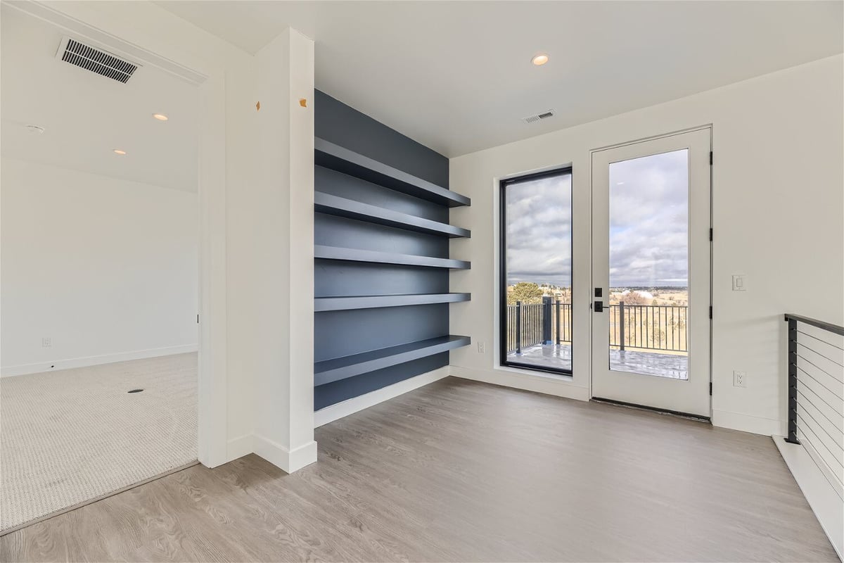 Second-floor loft with access to balcony and a view of hallway railing in a custom home by Sheffield Homes in Franktown, CO