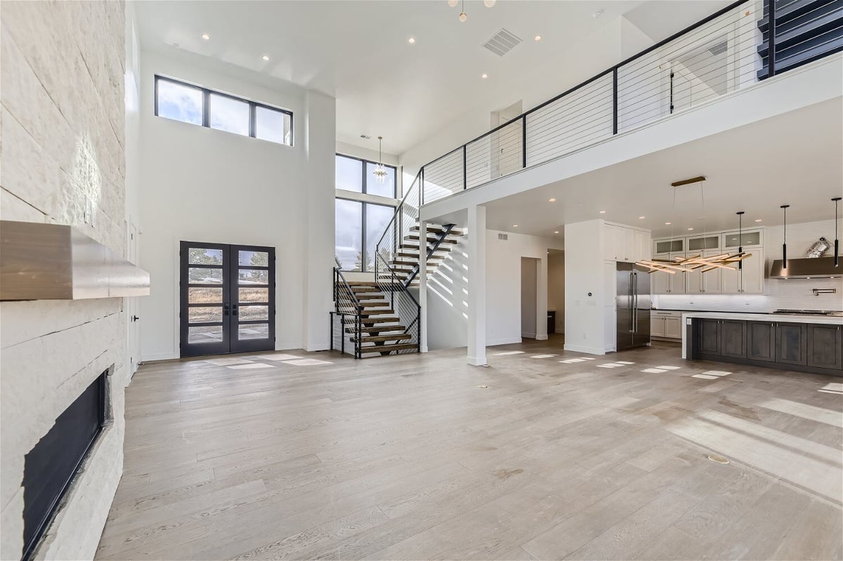 Spacious living room with a foyer, open kitchen, and an access door in a custom home by Sheffield Homes in Franktown, CO