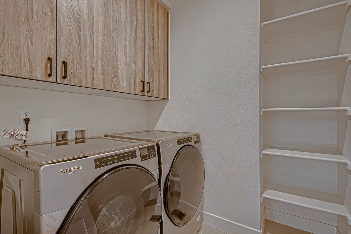 Compact laundry room with washing machines and cabinetry for storage in a custom home by Sheffield Homes in Louisville, CO