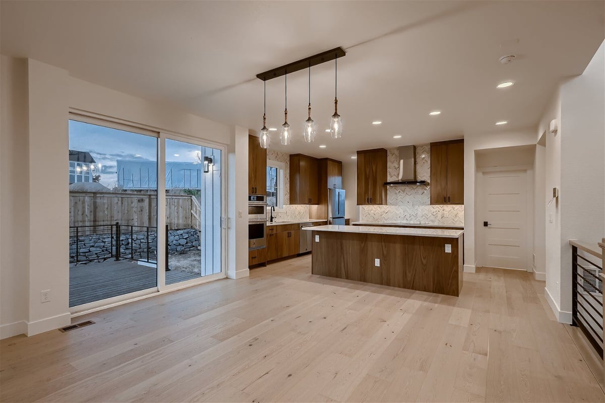 Living room breakfast area with large sliding doors and an open kitchen in a custom home by Sheffield Homes in Louisville, CO