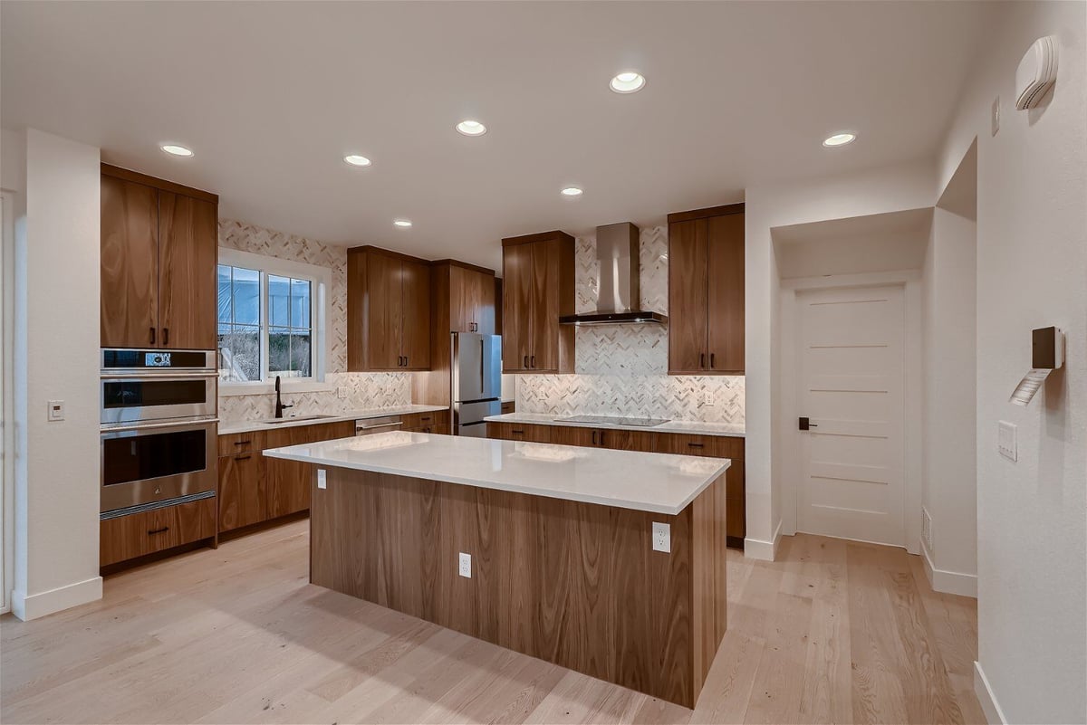 Modern kitchen with an island, cabinetry, and stove fixtures in a custom home by Sheffield Homes in Louisville, CO