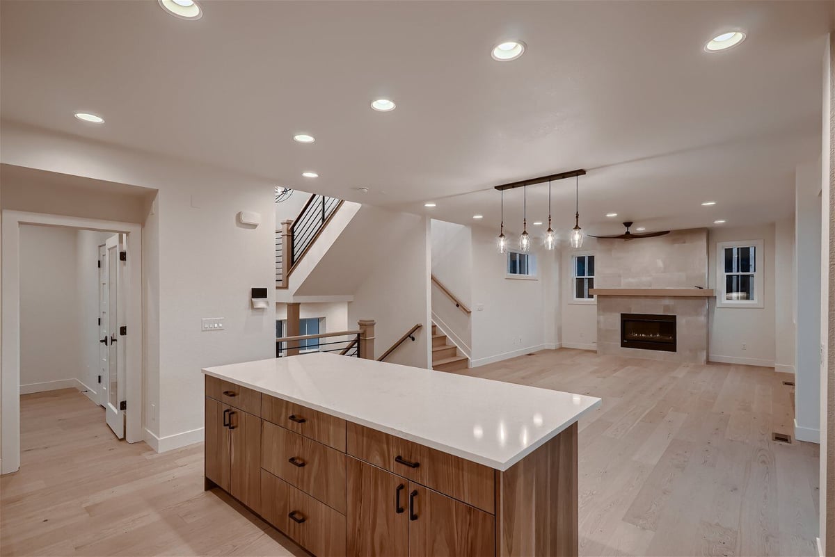 Open kitchen with a sleek countertop island and natural wood cabinetry in a custom home by Sheffield Homes in Louisville, CO