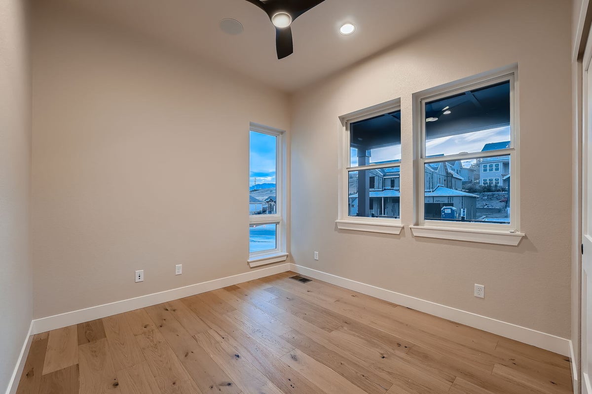 Bright bedroom with hardwood flooring and large windows in a Denver custom home by Sheffield Homes