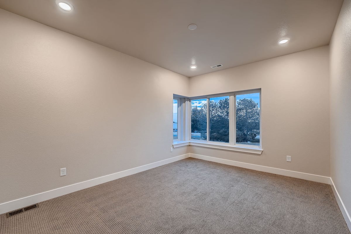 Lower level bedroom with natural light and carpet flooring in a custom Denver home by Sheffield Homes