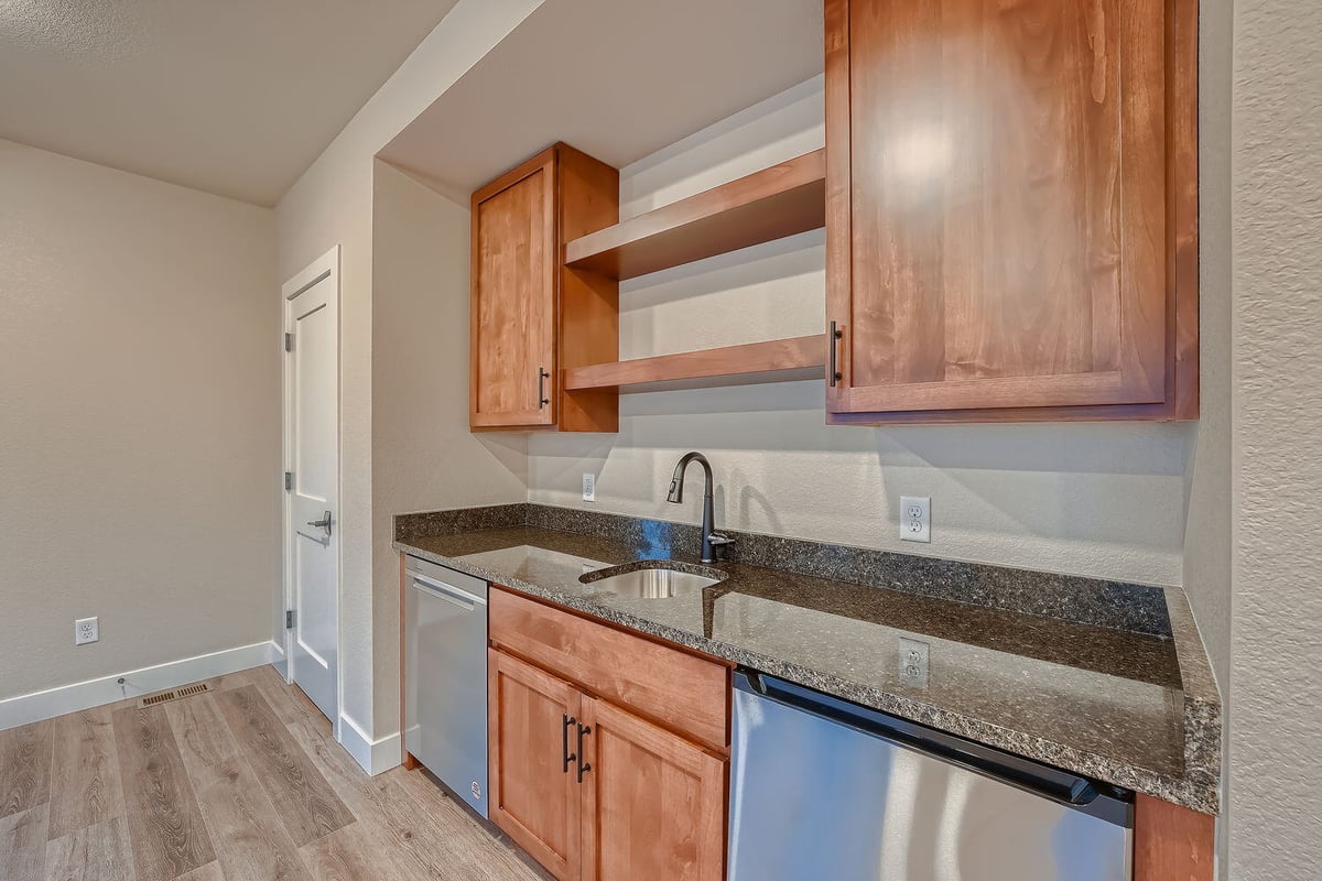 Lower level wet bar with wood cabinetry and granite countertop in a custom Denver home by Sheffield Homes