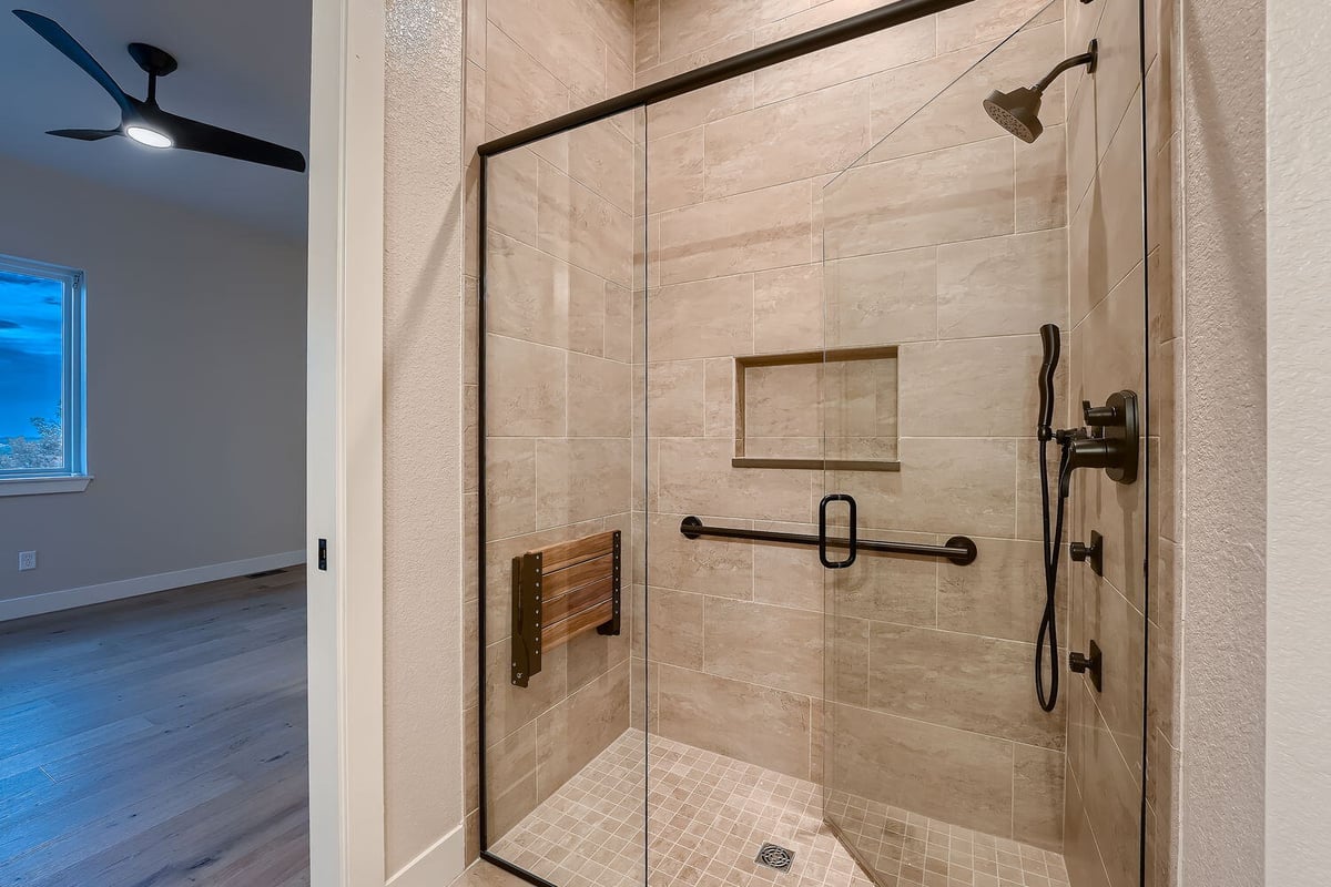 Modern walk-in shower with glass enclosure and grab bars in a custom home by Sheffield Homes, Denver