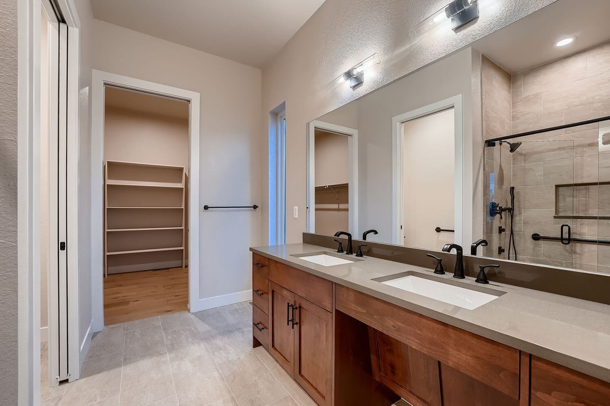 Primary bathroom with dual vanity and wood cabinetry in a Sheffield Homes custom Denver home