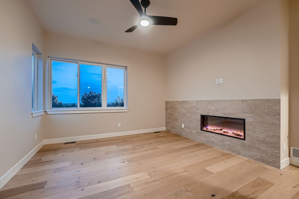 Primary bedroom with built-in electric fireplace and view of the outdoors, Denver custom home by Sheffield Homes