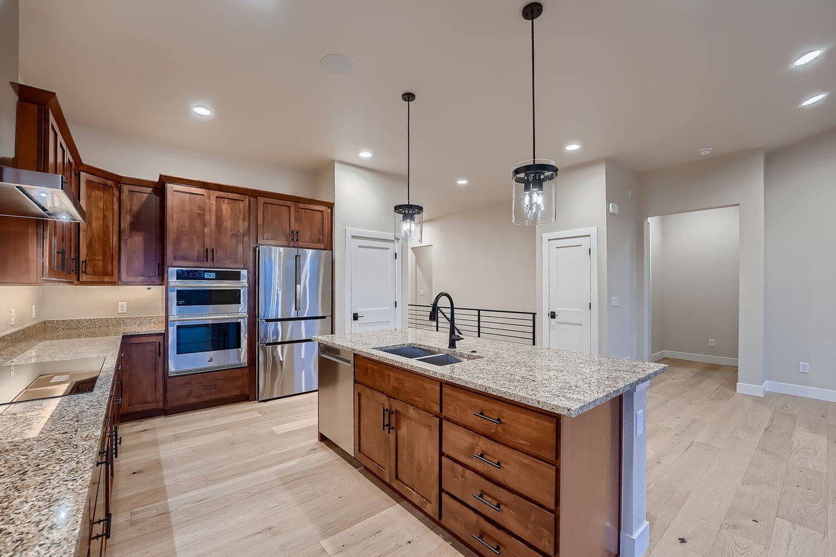 Spacious custom kitchen with granite countertops and modern lighting in a Denver home by Sheffield Homes