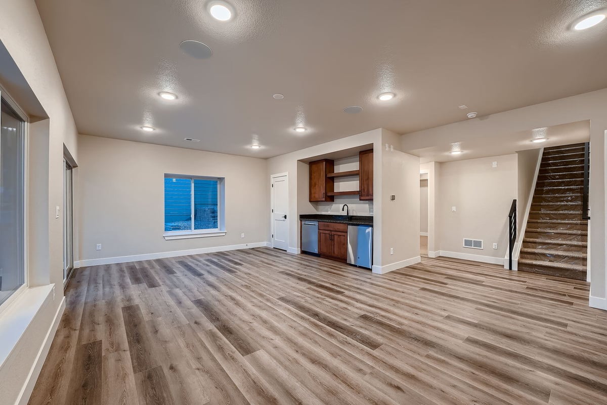 Spacious family room with wood flooring and kitchenette in a custom home by Sheffield Homes, Denver