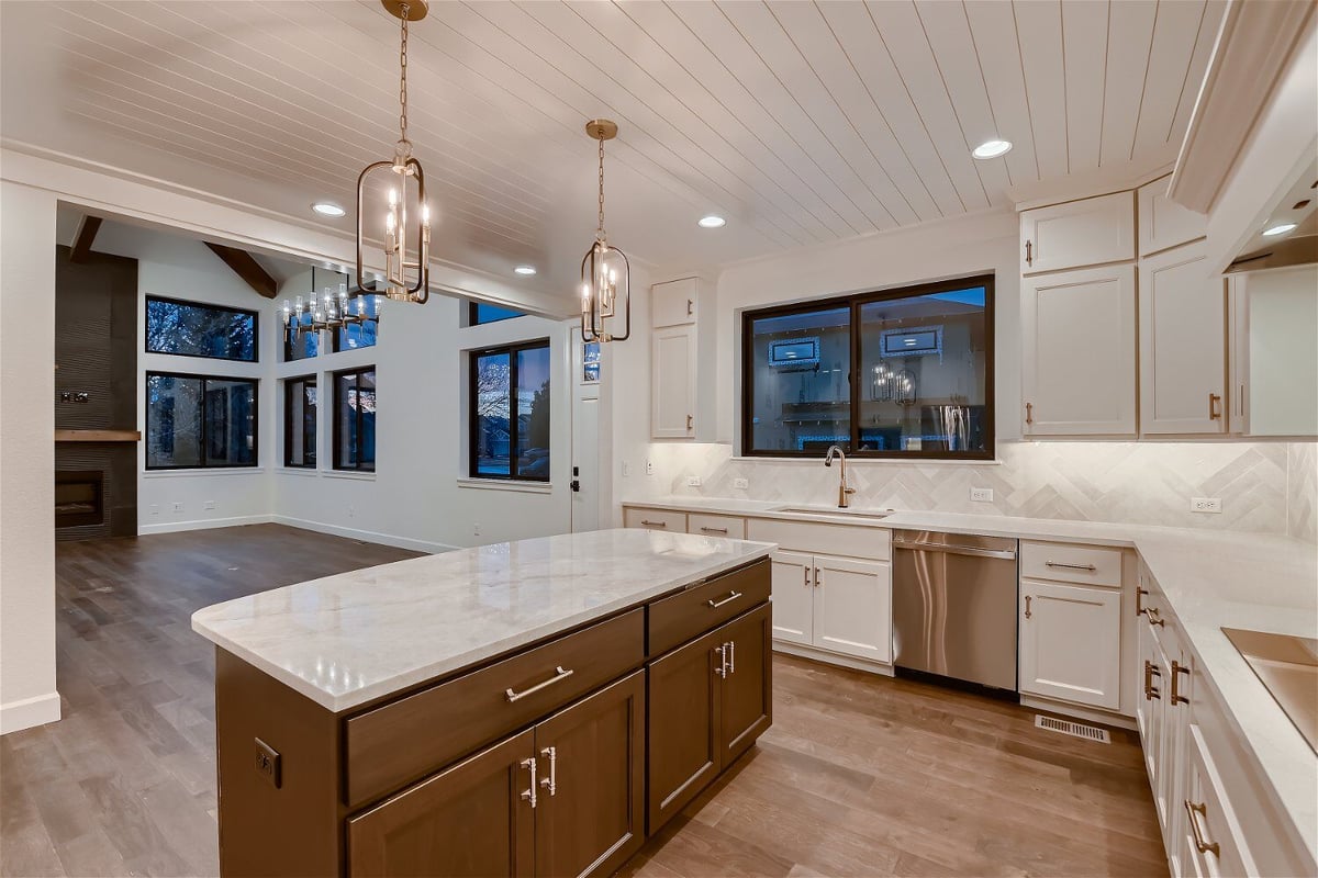 Close-up island with marble countertop and wooden base in an open kitchen of a home by Sheffield Homes in Louisville, CO