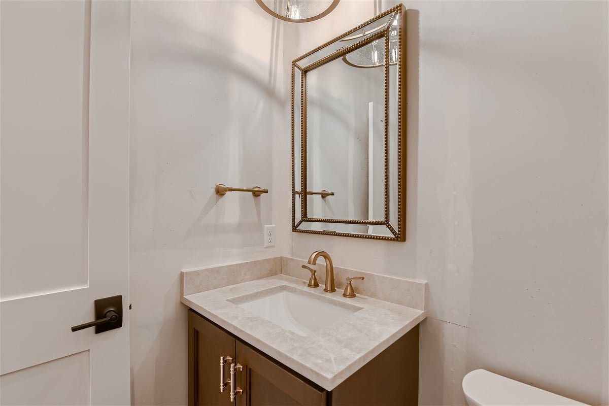 Cozy powder room with an elegant mirror and faucet fixtures in a custom home project by Sheffield Homes in Louisville, CO