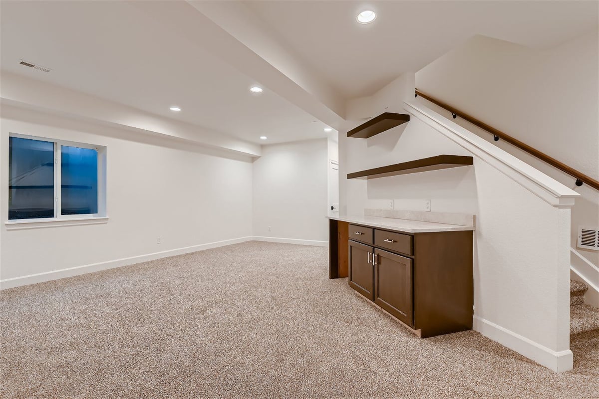 Family room with carpet flooring, a side dresser, and a sliding window in a custom home by Sheffield Homes in Louisville, CO