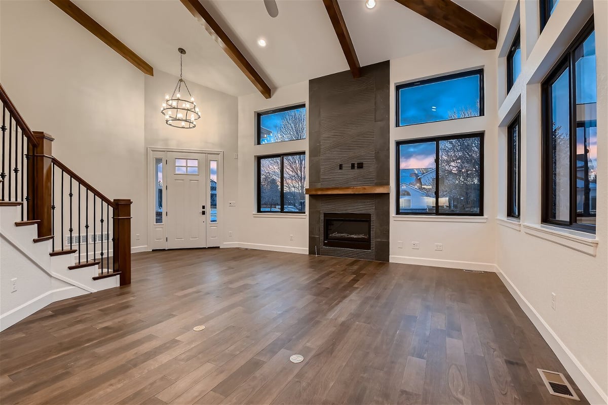 Living room with a back foyer view, chandelier, and fireplace corner in a custom home by Sheffield Homes in Louisville, CO