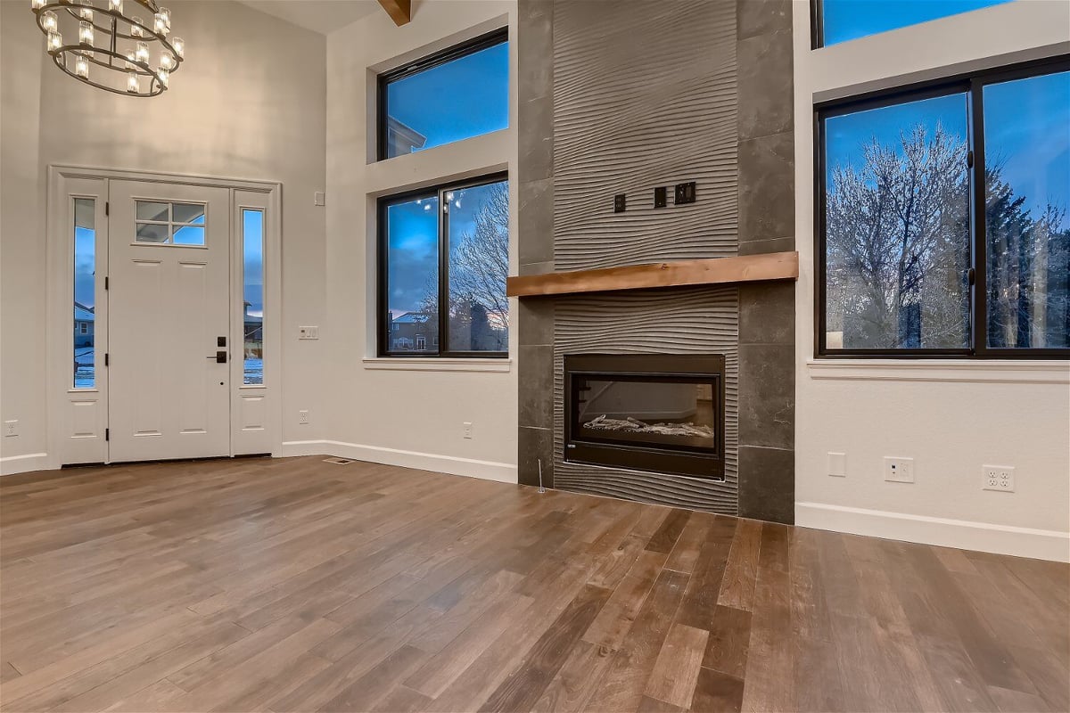 Living room with a unique wall, mounted fireplace, and sliding windows in a custom home by Sheffield Homes in Louisville, CO