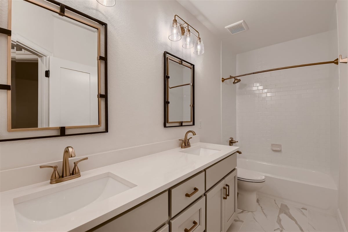 Modern bathroom with stylish dual vanities, a toilet, and a shower room in a Sheffield Homes home in Louisville, CO