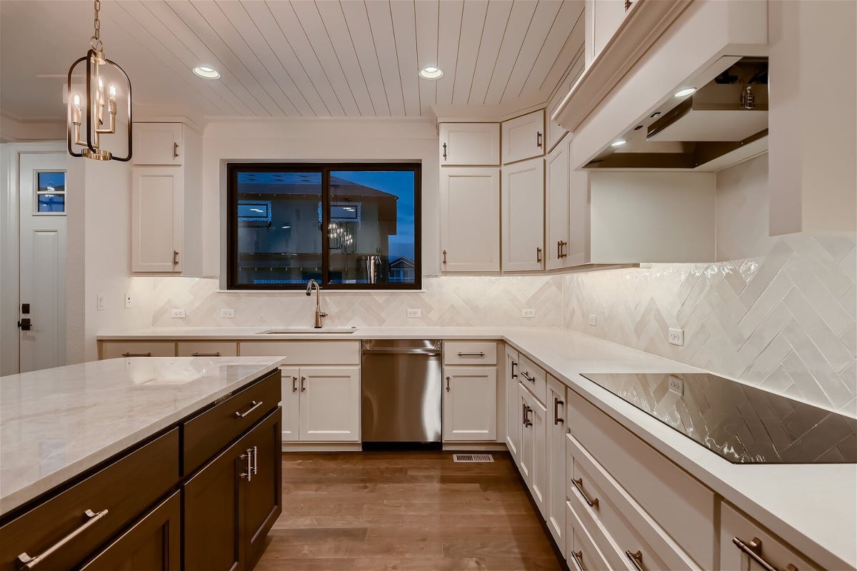 Modern kitchen with sleek white cabinetry and elegant lighting in a custom home by Sheffield Homes in Louisville, CO