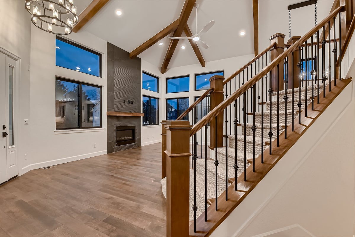 Sideview of a living room stairway featuring carpeted steps and wood railings in a home by Sheffield Homes in Louisville, CO