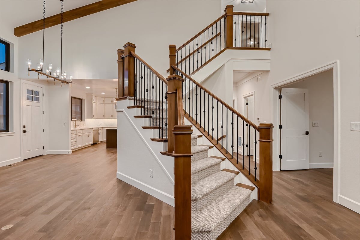 Stairway with carpeted steps and elegant wood railings in the living room of a home by Sheffield Homes in Louisville, CO