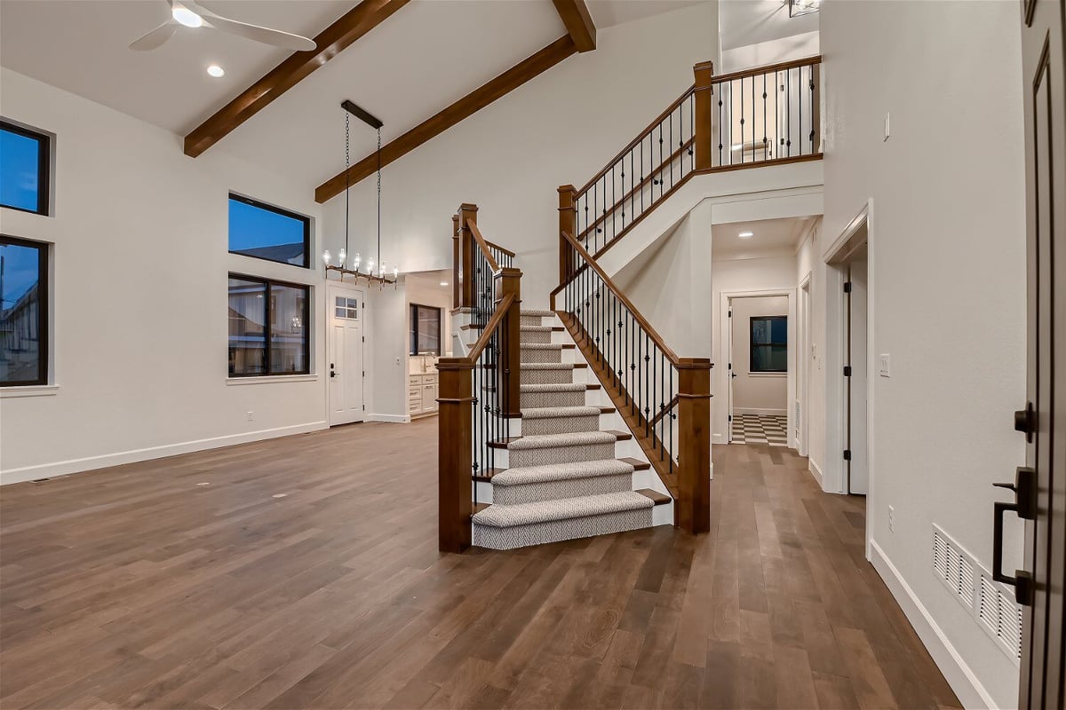 Stylish foyer with carpeted stairs, wooden railings, and metal fencing in a custom home by Sheffield Homes in Louisville, CO