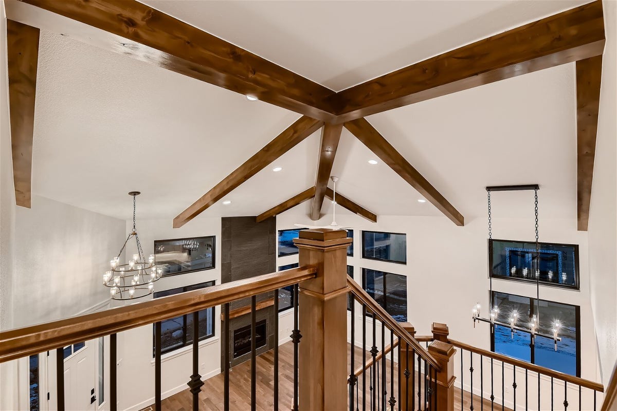 View of the hall from the staircase featuring a wooden ceiling design in a custom home by Sheffield Homes in Louisville, CO