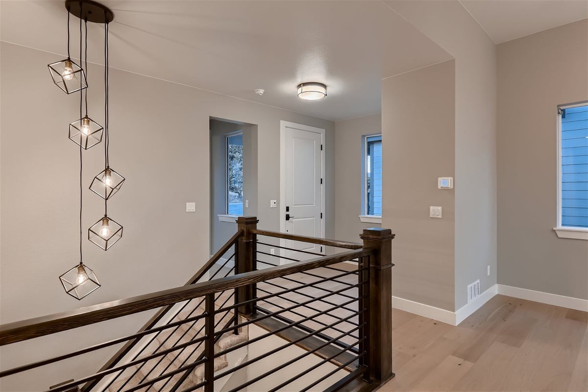 Bright foyer with wooden railings, a fancy chandelier, and elegant lighting in a custom home by Sheffield Homes in Louisville, CO