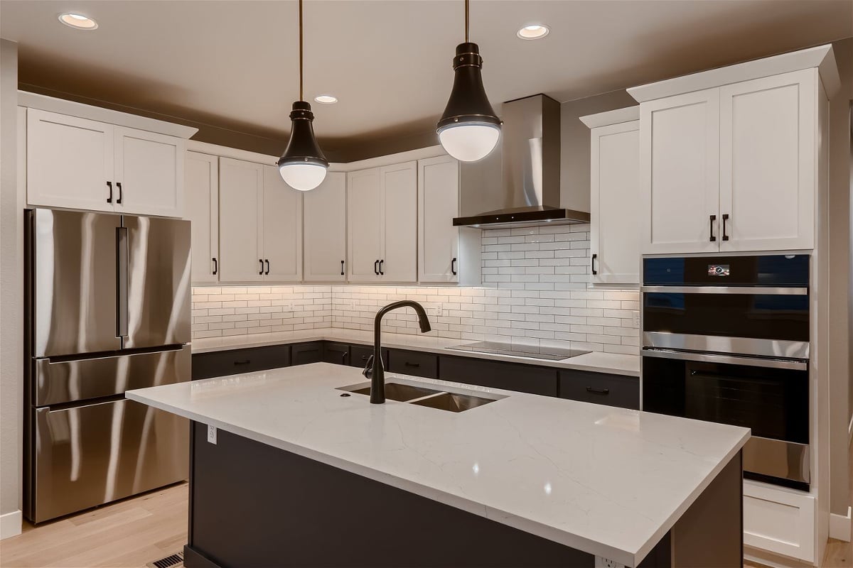 Closeup of a modern kitchen island with sleek countertop, faucet, and pendant lighting, by Sheffield Homes in Louisville, CO