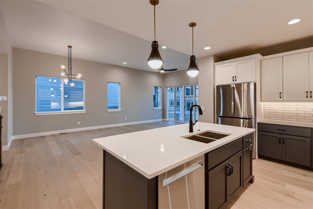 Kitchen island with a marble countertop, wooden and steel cabinets, and pendant lighting - by Sheffield Homes, Louisville, CO