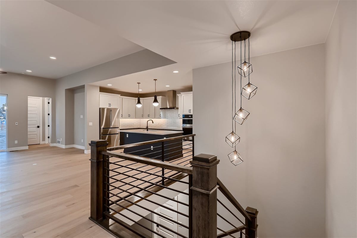 Stairway with wood railings, a metal fence, and a chandelier on the upper floor in a Sheffield Homes home in Louisville, CO