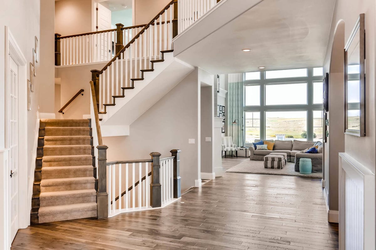 Bright stairways with carpeted steps and wooden railings in a custom home project by Sheffield Homes in Parker, CO