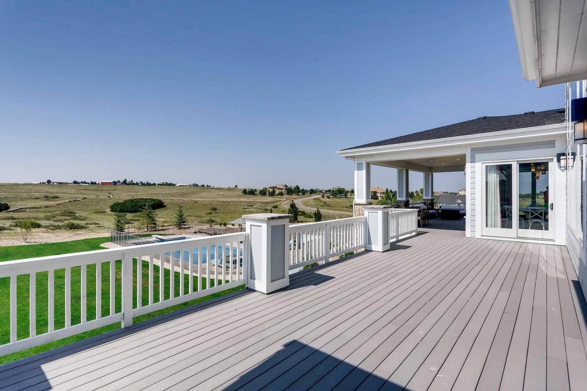 Deck with white wooden fence offering elevated views of outdoor greenery from a custom home by Sheffield Homes in Parker, CO