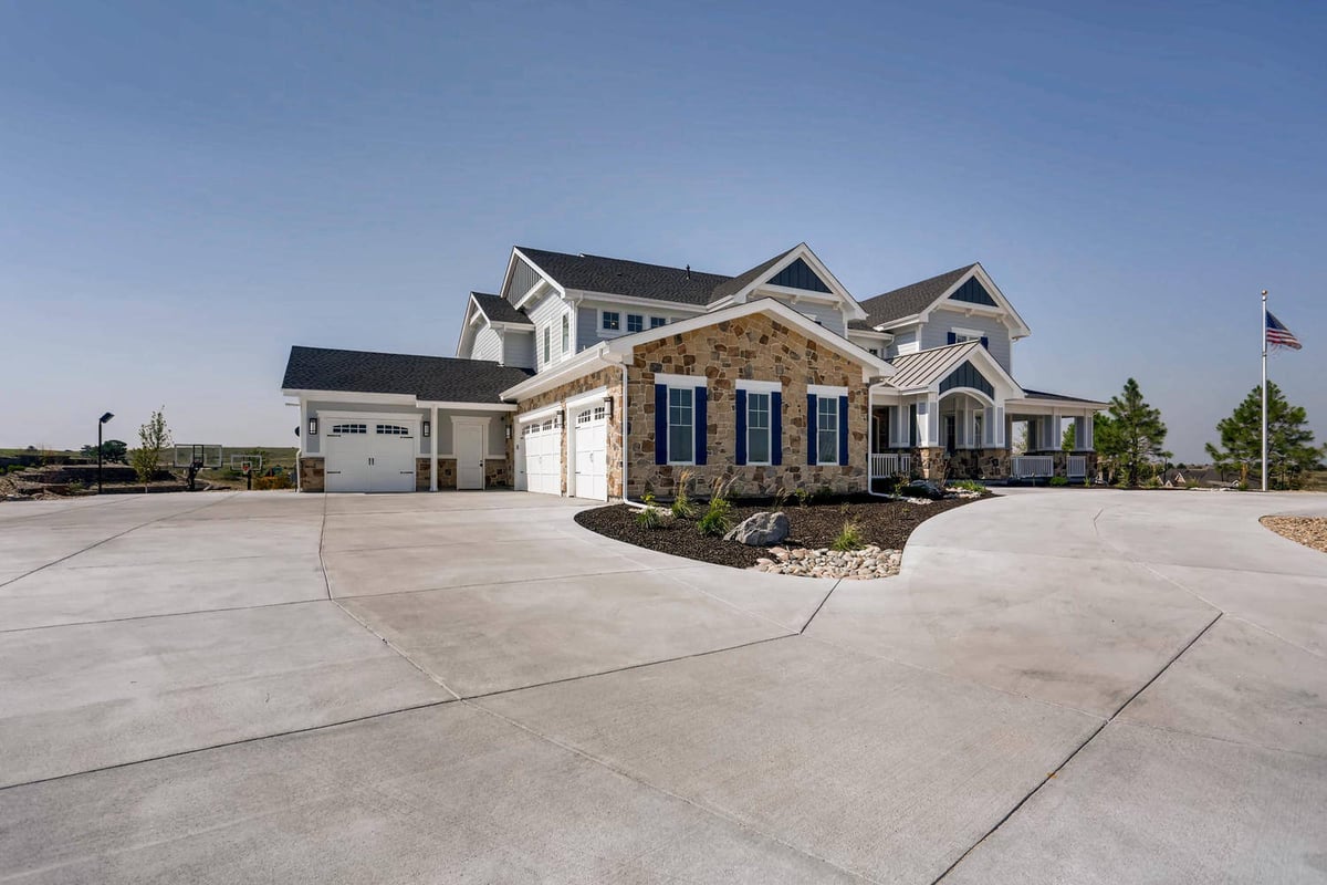 Exterior front shot of a large custom-designed home with a paved driveway and mini lawn by Sheffield Homes in Parker, CO