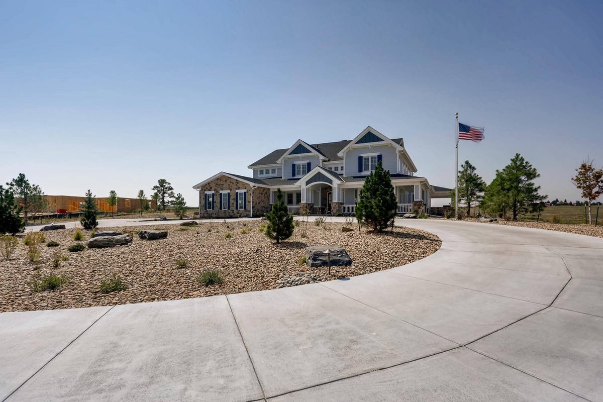 Exterior front wide shot of a large custom home with a paved driveway by Sheffield Homes in Parker, CO