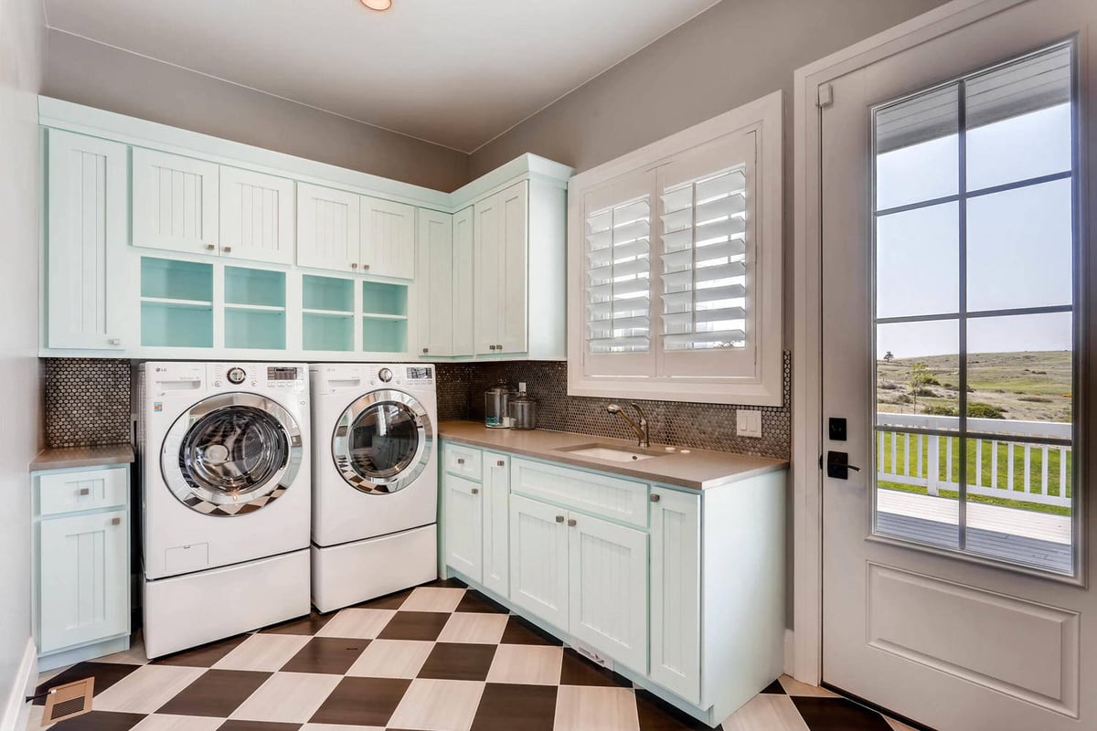 Laundry room with washing machines, a wash basin sink, and cabinetry for storage in a Sheffield Homes home in Parker, CO